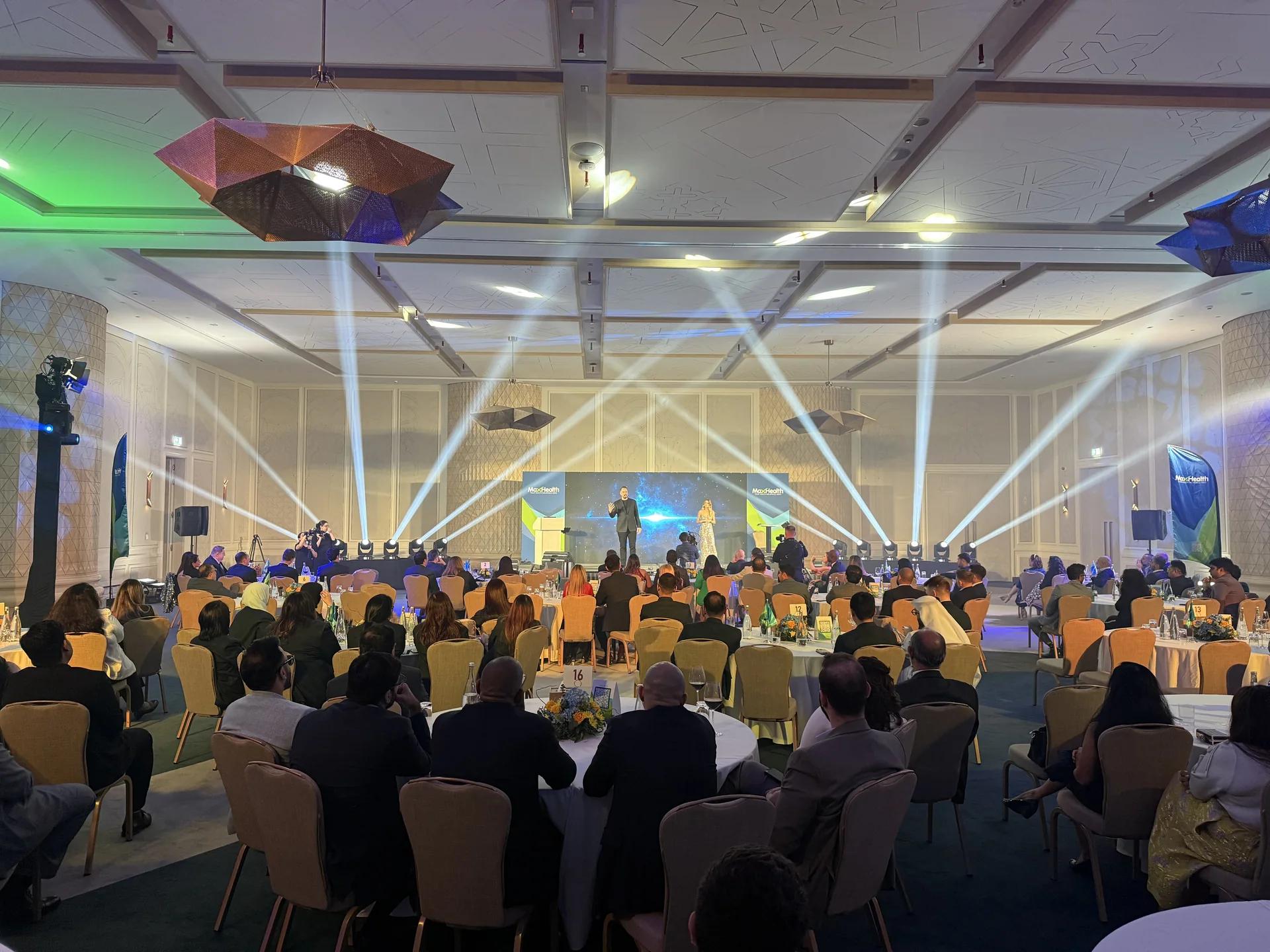 Gala room with audience tables, a live stage and programmed lighting.