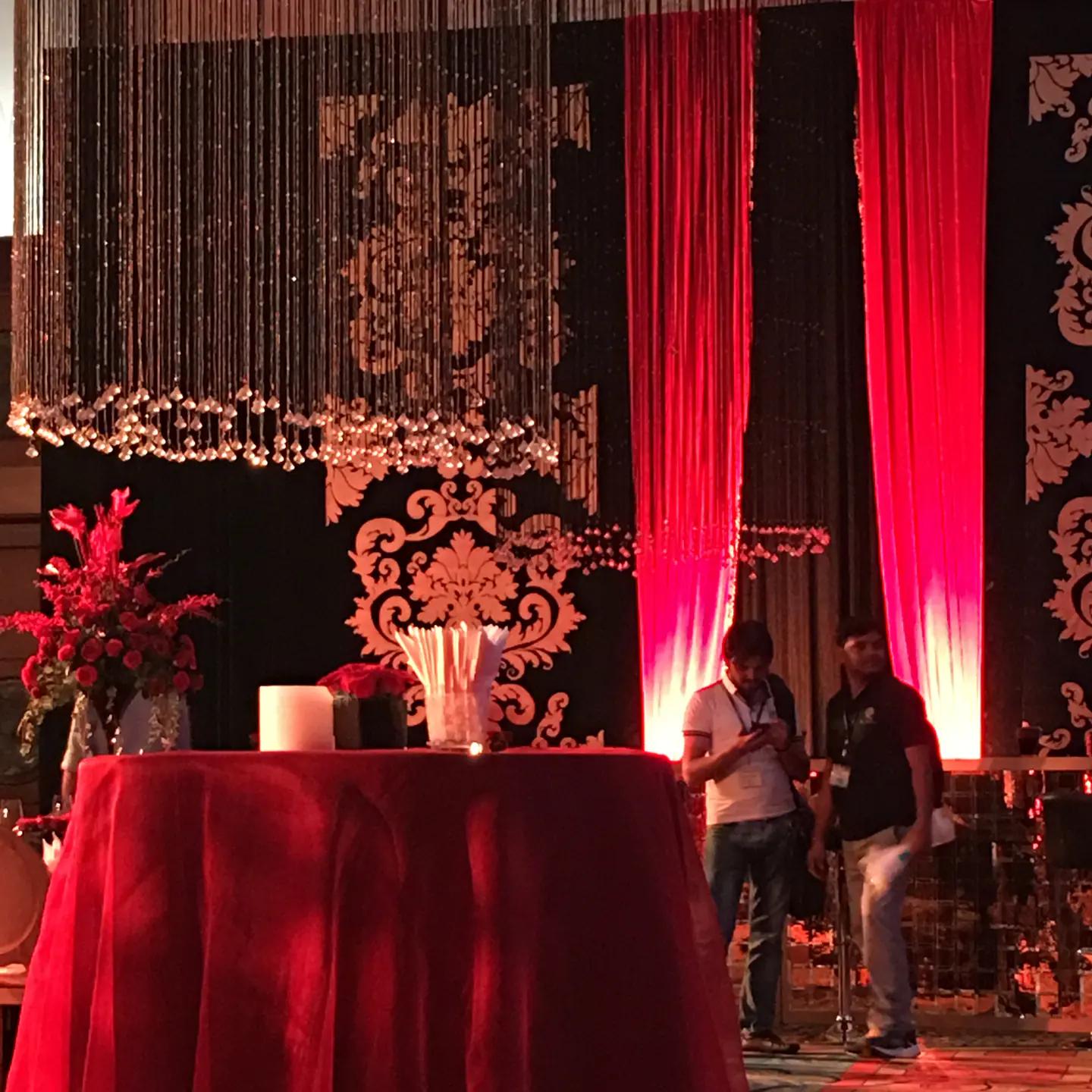 Decorated celebration stage with crystal strands, draping and floral arrangements.