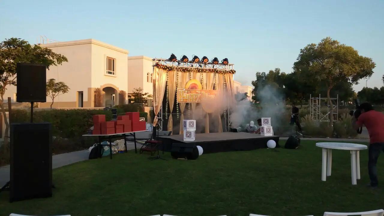 Outdoor event lawn with a compact stage and open guest seating.