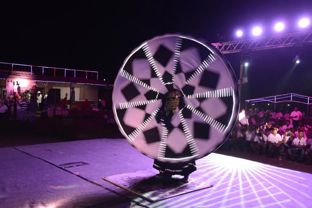 Illuminated spinning performance on a night-time outdoor stage.