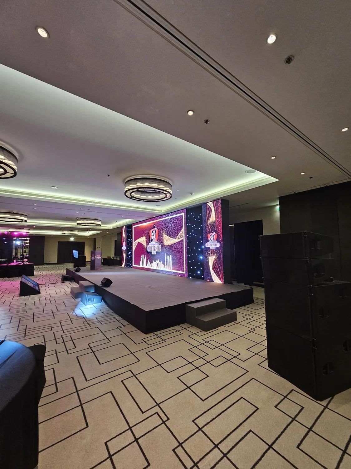 Corporate room setup with stage, screens and banquet seating