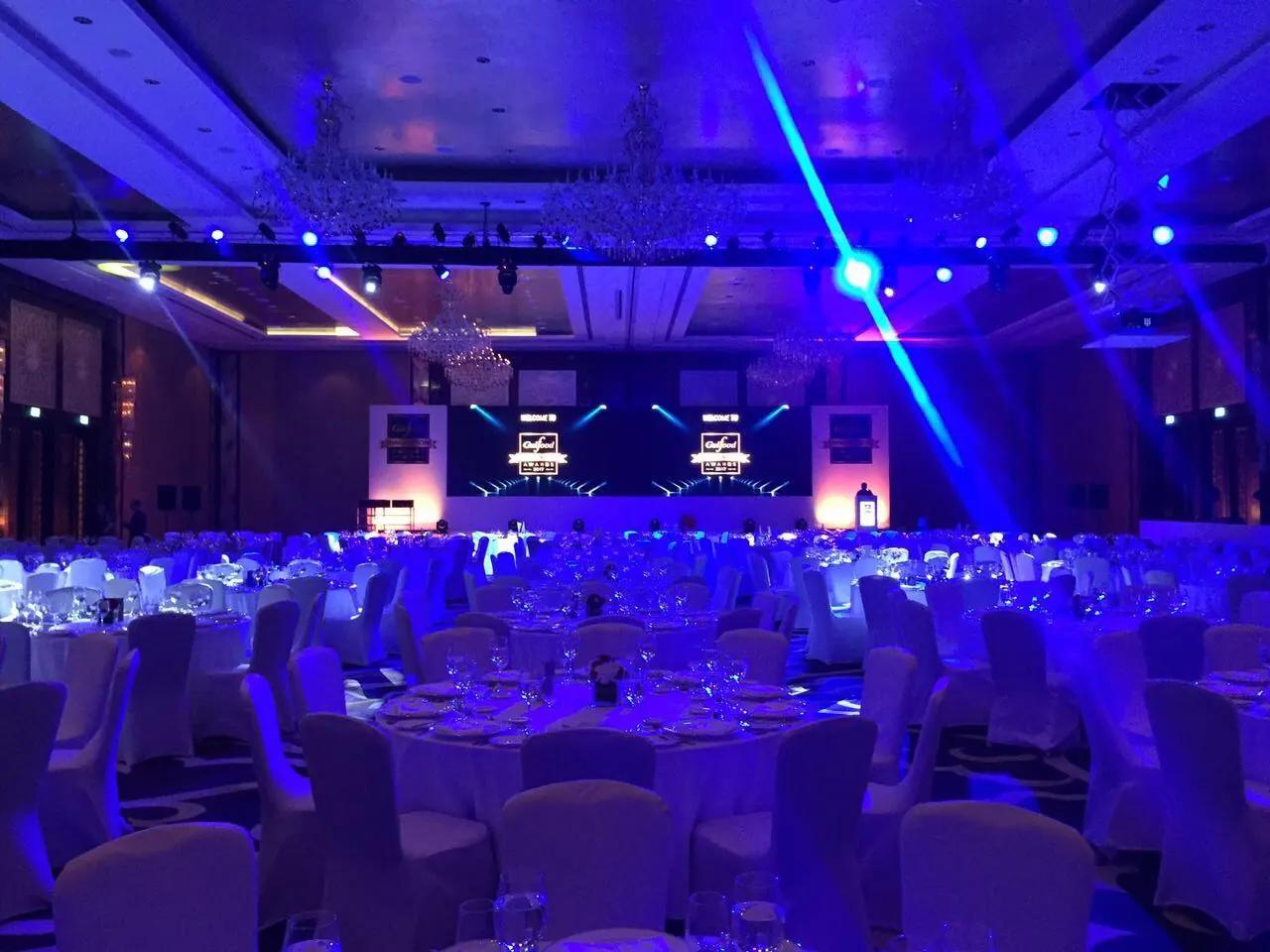 Stage beams and overhead lighting fixtures operating inside a live event hall