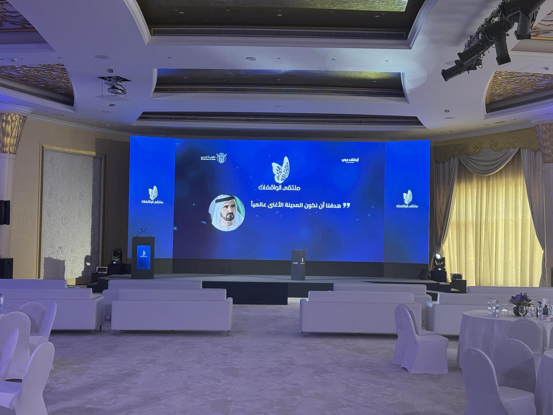 International conference stage with a wide LED screen and guest seating.
