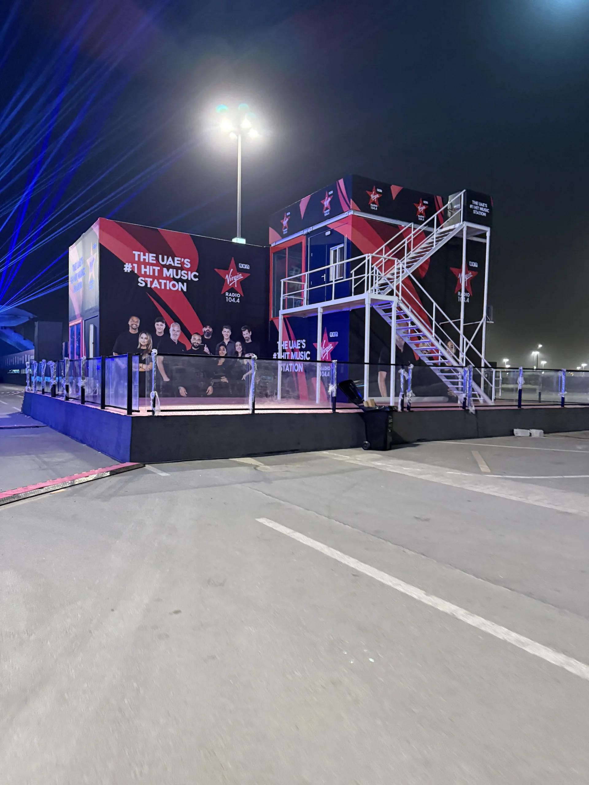 Large outdoor branded structure with an elevated platform and technical access.