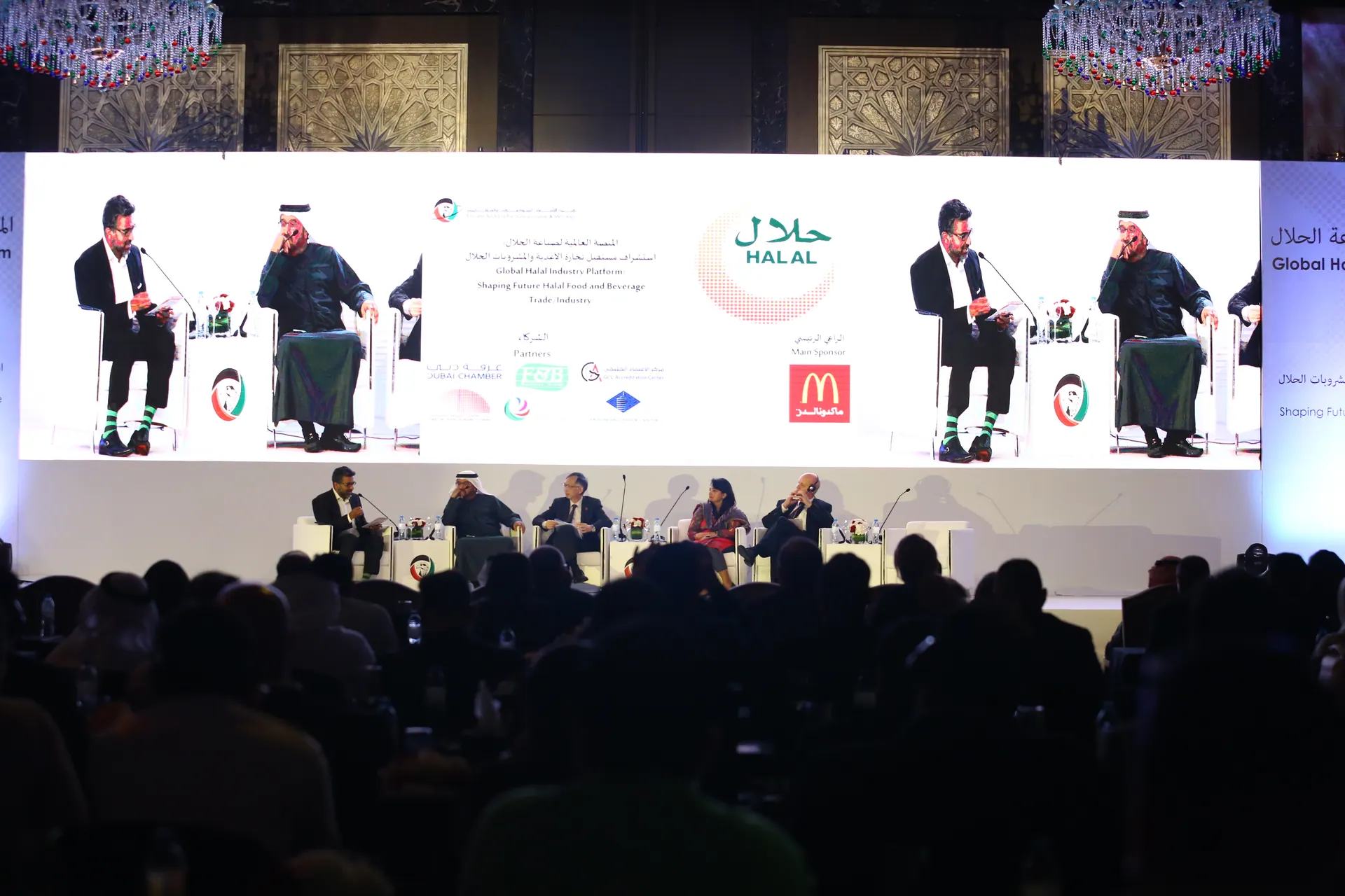 Wide corporate stage with presentation screens, scenic lighting and delegate seating.